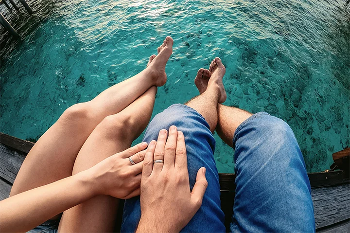 Couple célébrant leur voyage de noces aux Maldives au bord d’une villa sur pilotis
