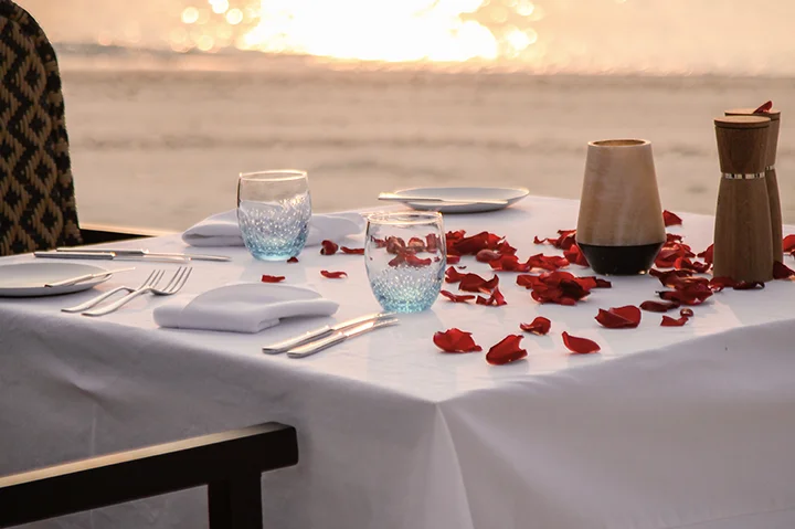 Table dressée pour un diner romantique sur la plage au coucher du soleil