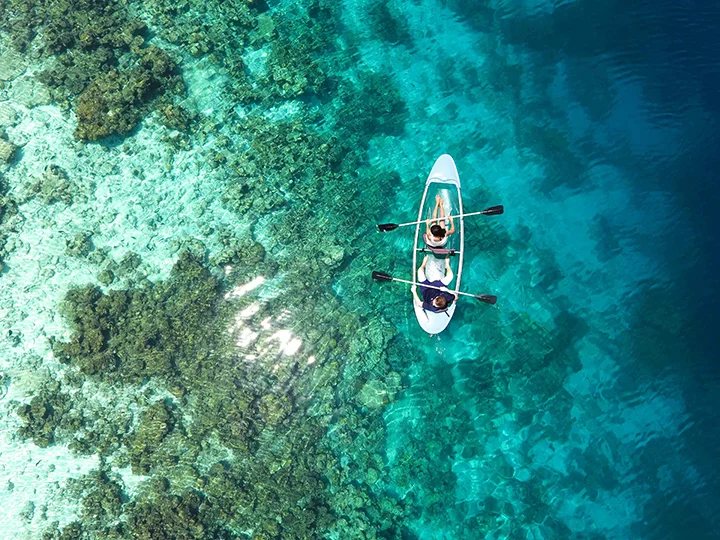 Couple faisant du kayak transparent sur un lagon